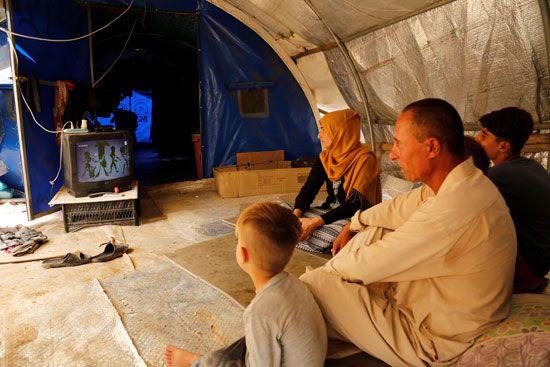 61122-أسرة-عراقية-نازحة-تشاهد-التلفاز-في-خيمتهم-في-مخيم-الخازر-للاجئين-على-مشارف-أربيل