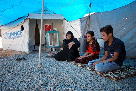 78252-امرأة-عراقية-نازحة-تجلس-مع-أبنائها-خارج-خيمتهم-في-مخيم-حسن-شام