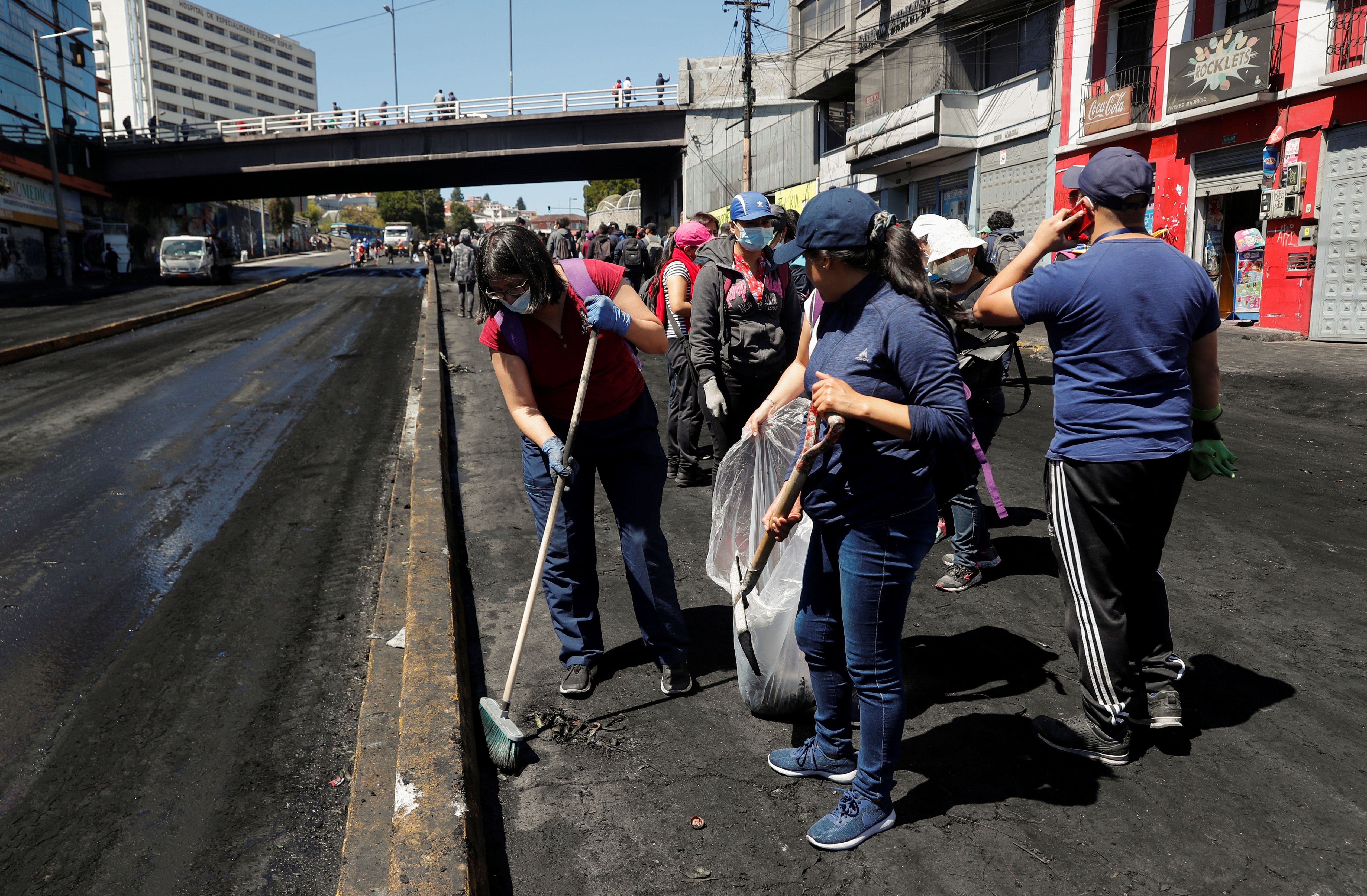 الناس ينظفون الحطام من الشوارع في أعقاب احتجاجات الأيام الأخيرة