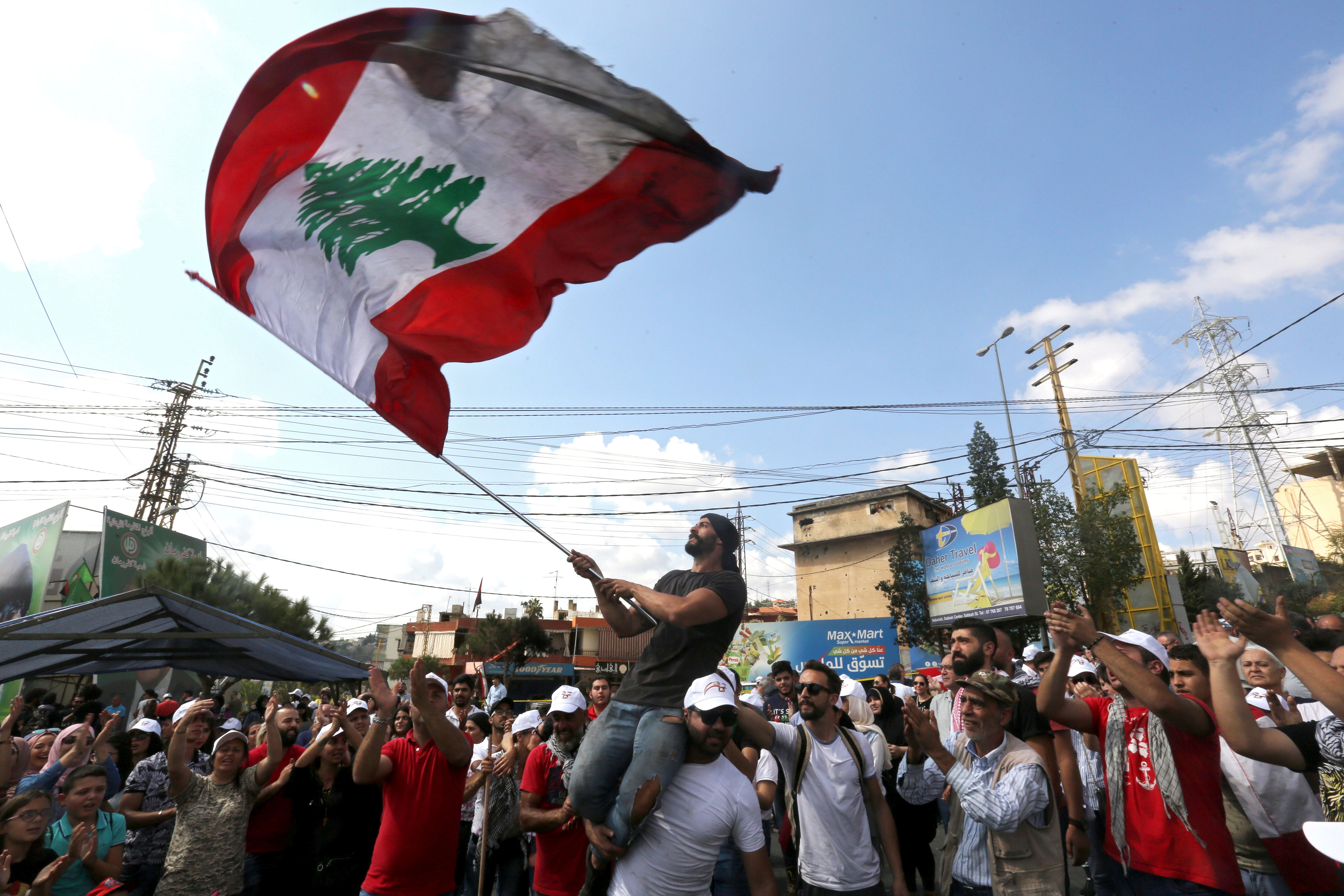 متظاهر يلوح بعلم وطني خلال مظاهرة  في مدينة النبطية الجنوبية