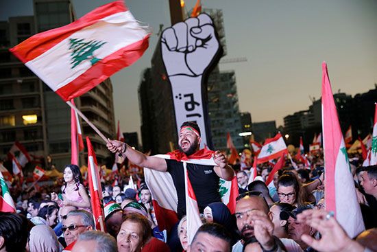 المتظاهرون يحملون الأعلام اللبنانية خلال الاحتجاجات المستمرة المناهضة للحكومة في بيروت