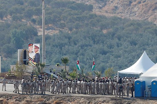 جنود أردنيون يتجمعون بالقرب من صورة للعاهل الأردني الملك عبد الله ووالده الراحل الملك حسين في المنطقة الحدودية بين إسرائيل والأردن
