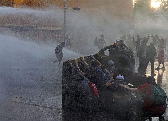 مجموعة متظاهرين يحتمون بأحد الحواجز من دخان الغاز