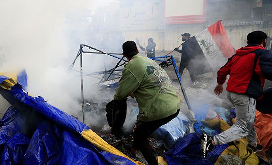 الدخان ينبعث من خيام مشتعلة بينما تهاجم قوات الأمن العراقية ميدان التحرير خلال الاحتجاجات