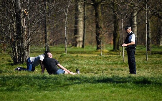 ضابط شرطة يتحدث مع رجلين ليغادرا الحديقة