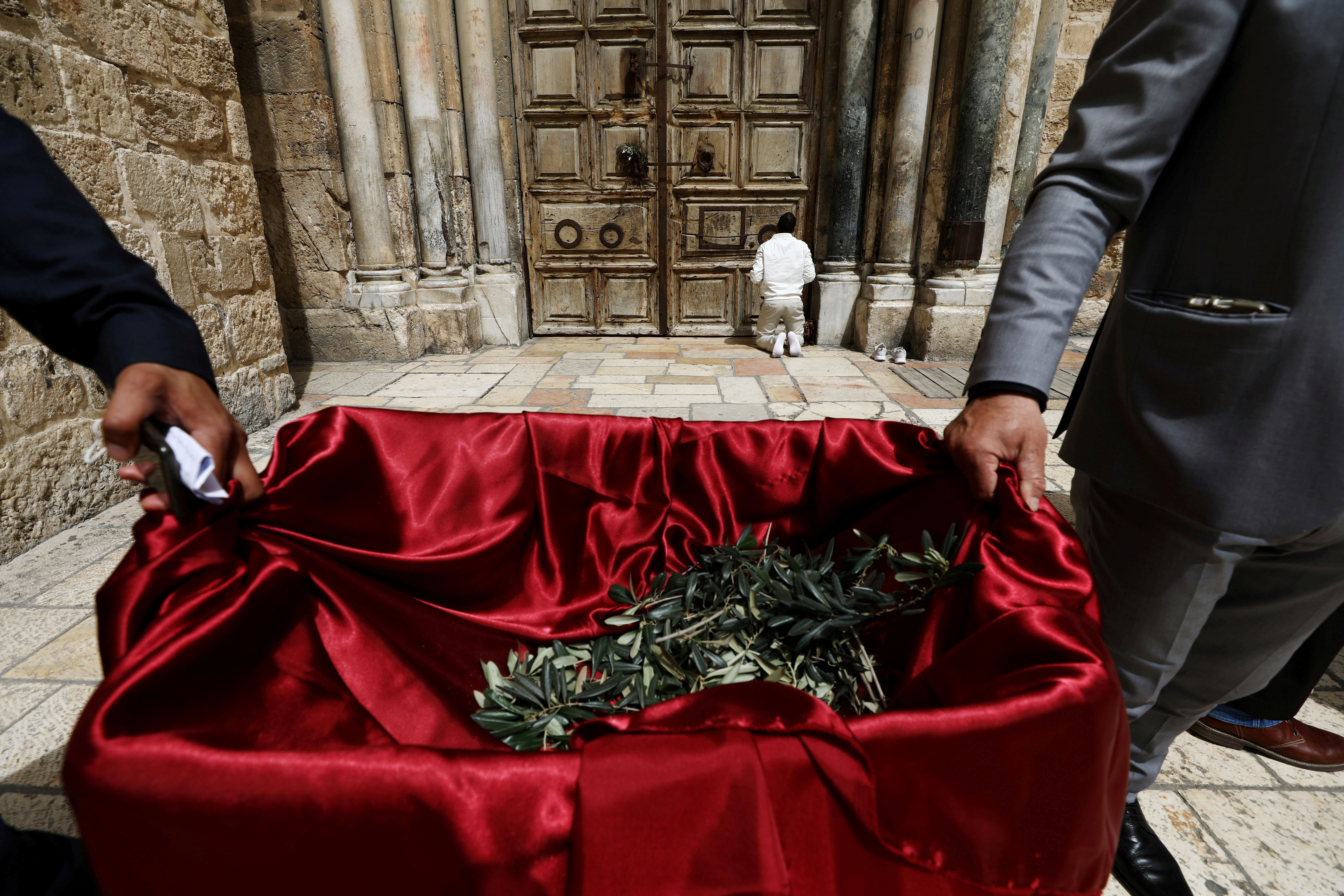 رجل يصلي أمام الأبواب المغلقة لكنيسة القيامة خلال أسبوع الآلام  في القدس