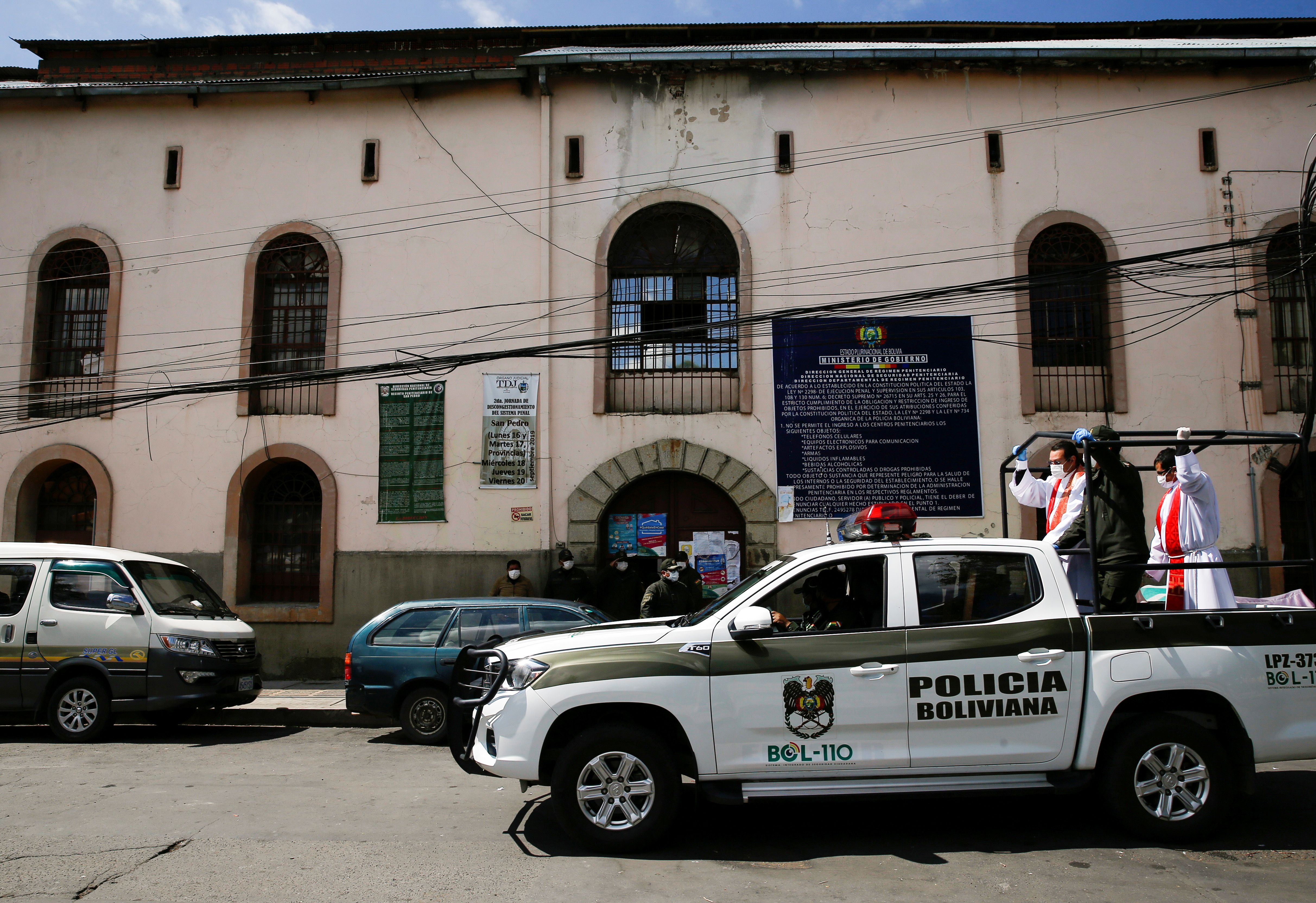 الكهنة على سيارة شرطة يباركون رجال الشرطة أمام سجن سان بيدرو خلال احتفال أحد السعف في لاباز