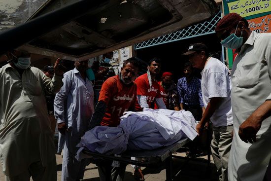 عمال الإنقاذ وأقاربهم ينقلون جثة ضحية قتل في حادث تحطم طائرة في كراتشي