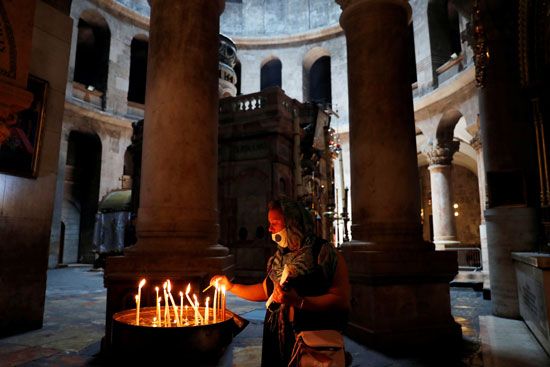 زائرة تشعل الشموع داخل كنيسة القامة