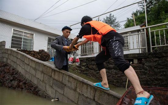 رجل إنقاذ يمنح أحد السكان المتضررين المياة