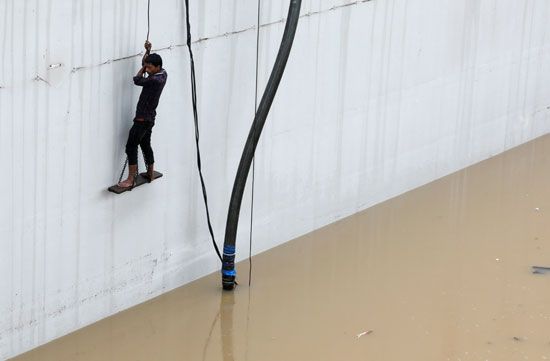 شخص يتسلق على الحبال بسبب ارتفاع منسوب مياه الأمطار