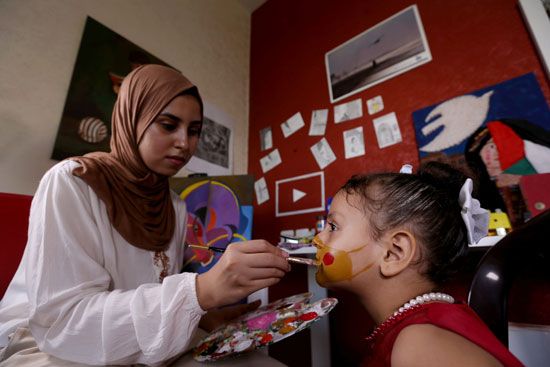الطفلة ترسم قناعا على وجهها للتوعية بأهمية ارتدائه الطفلة ترسم قناعا على وجهها للتوعية بأهمية ارتدائه