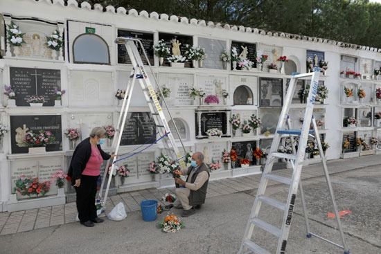يقوم الناس بإعداد الزهور لوضعها على شاهد قبر أقاربهم
