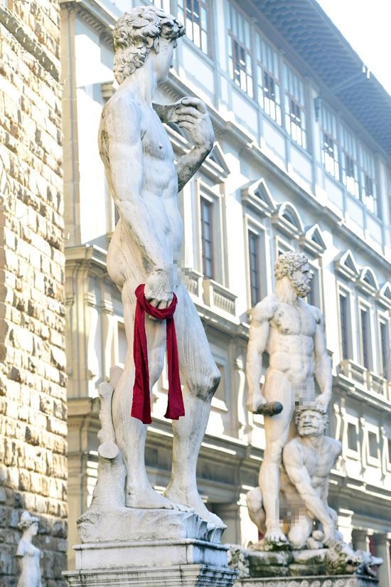 تمثال مايكل أنجلو وهو يحمل وشاحًا أحمر احتفالًا باليوم لمناهضة العنف ضد المرأة