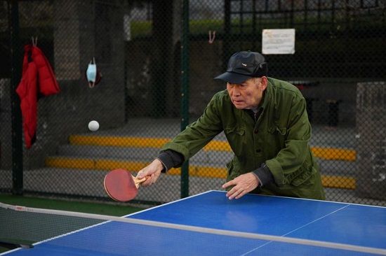 رجل مسن يلعب تنس الطاولة في حديقة في بكين