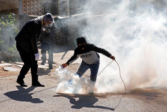 فلسطيني يمسك بقنبلة غاز