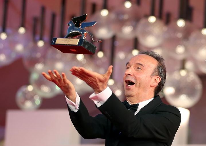الممثل روبرتو بينيني يقف مع جائزة الأسد الذهبي لإنجازه مدى الحياة على السجادة الحمراء لحفل الافتتاح