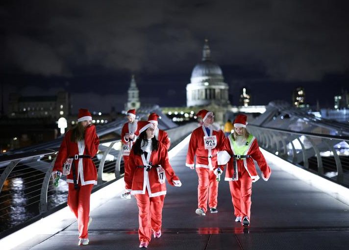 أشخاص يرتدون زي بابا نويل يمشون فوق جسر الألفية في لندن