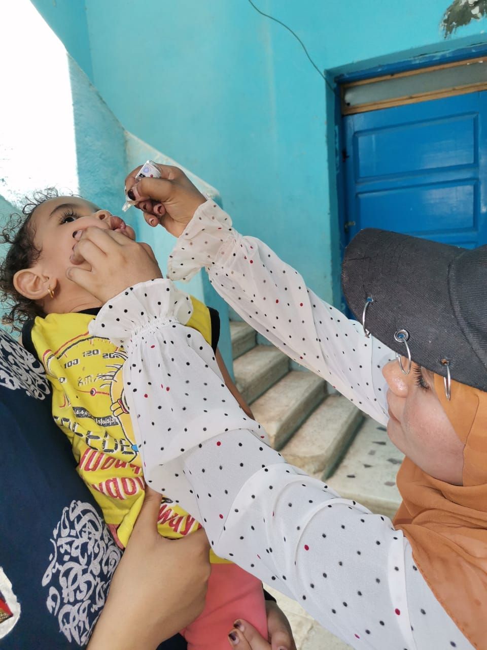 طفلة خلال تلقى التطعيم أمام منزلها