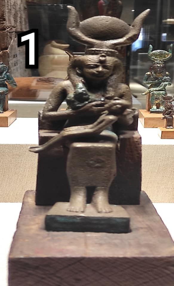 تمثال المعبودة (إيزيس ) وهي جالسة ترضع طفالها حورس ترتدي التاج الحتحوري يتوسطة قرص الشمس